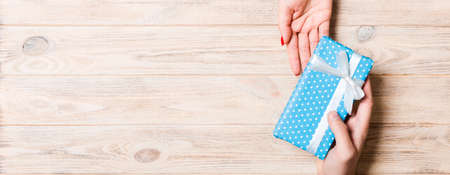 Top view of a man and a woman holding a gift box on wooden background. Love and relationship...