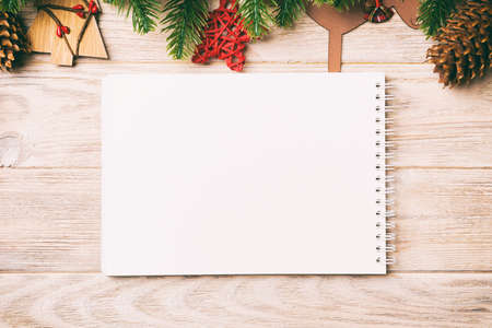 Top view of notebook, Christmas toys, decorations and fir tree branches on wooden background. New Year holiday concept.の写真素材