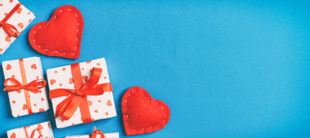 Holiday composition of gift boxes and red textile hearts on colorful background with empty space for your design. Top view of Valentine's Day concept.の写真素材