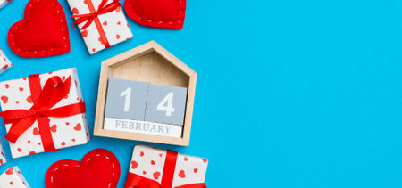 Holiday composition of gift boxes, wooden calendar and red textile hearts on colorful background...