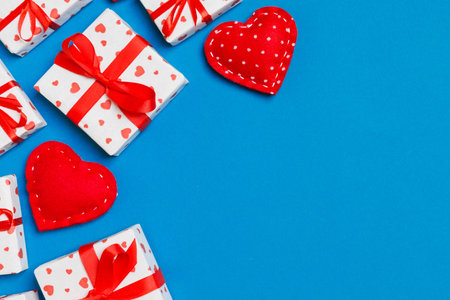 Top view of festive gift boxes and red textile hearts on colorful background with copy space. St...