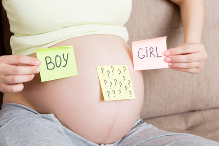 pregnant woman holding square multicolored stickers with question marks.の写真素材