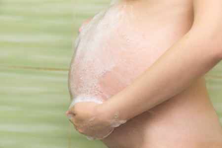 pregnant girl washes her belly in the shower.の写真素材