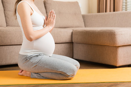 Beautiful pregnant woman doing yoga at home. Pregnancy Yoga and Fitness concept at coronavirus time.の写真素材
