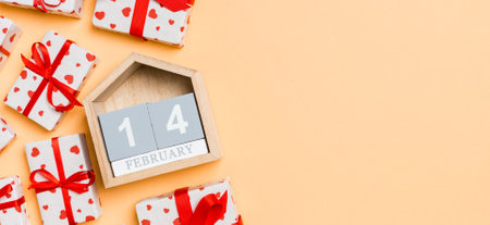 Holiday composition of gift boxes with red hearts and wooden calendar on colorful background with empty space for your design. The fourteenth of February. Top view of Valentine's Day concept.の写真素材