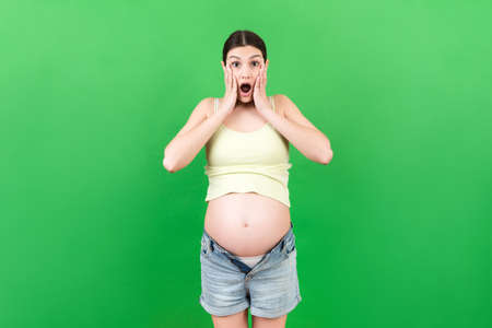 pregnant woman in unzipped jeans showing her naked belly at colorful background with copy space. Baby expecting concept.の写真素材
