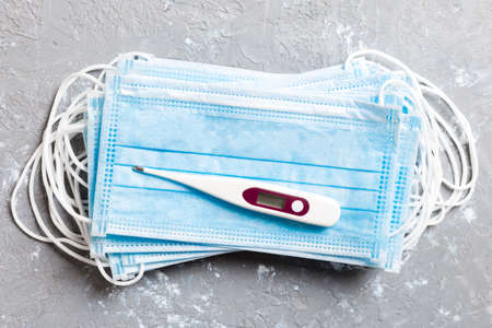 Epidemic background of protective medical masks and a thermometer on colored background. World...
