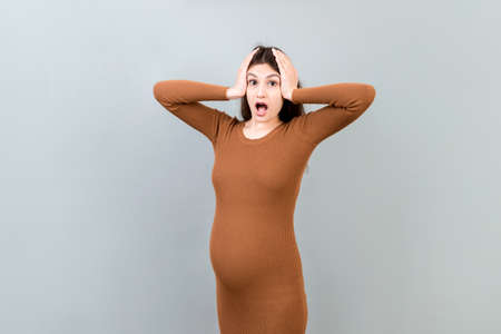 Young surprise or shocked woman pregnant isolated colored background. expression female.の写真素材
