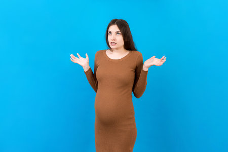 Young beautiful teenager girl pregnant expecting baby over isolated colored background, aggressive expression and arms raised. Frustration concept.の写真素材