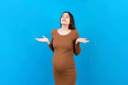 Young beautiful teenager girl pregnant expecting baby over isolated colored background, aggressive...