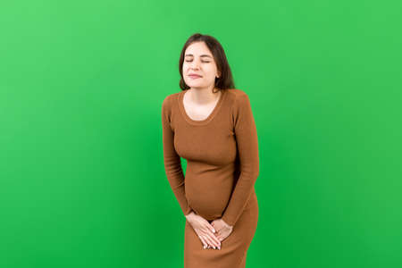 urinary incontinence during pregnancy. Abdominal pain during pregnancy. Maternity healthcare concept on colored background.の写真素材