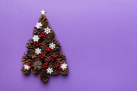 Christmas tree made from natural cones on colored background, view from above. New Year minimal concept with copy space.の写真素材