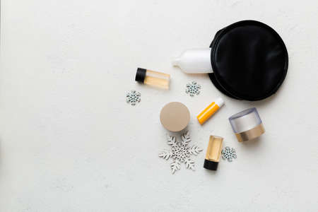 Christmas flat lay with makeup cosmetic products in cosmetic bag on colored background. Top view New year Beauty concept.の写真素材