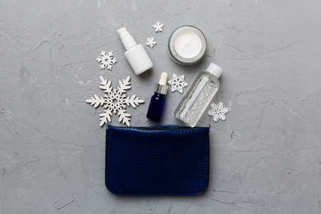 Christmas flat lay with makeup cosmetic products in cosmetic bag on colored background. Top view New year Beauty concept.の写真素材