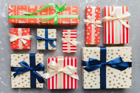 A lot of Christmas gift boxes in colored paper decorated on table, Top view close up. Many present...