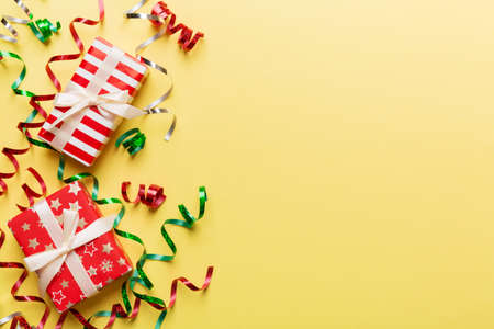 Holiday flat lay with gift boxes wrapped in colorful paper and tied decorated with confetti on colored background. Christmas, Birthday, Valentine and sale concept, top view.の写真素材