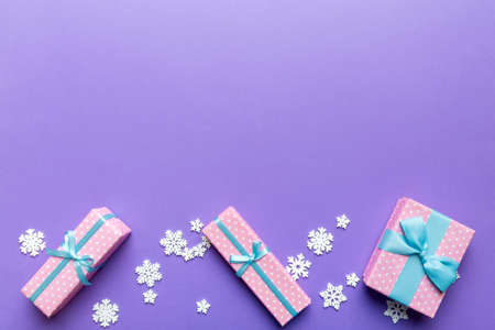 Holiday flat lay with gift boxes wrapped in colorful paper and tied decorated with confetti on colored background. Christmas, Birthday, Valentine and sale concept, top view.の写真素材