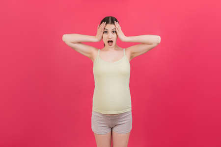 Young surprise or shocked woman pregnant isolated colored background. expression female.の写真素材