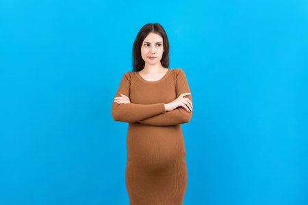 Pensive pregnant woman choosing name for baby on colored background. Dream and Happy Pregnant Woman Thinking Imagining Motherhood Life. Copy Space.の写真素材