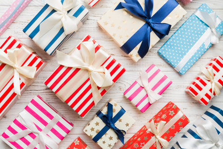 A lot of Christmas gift boxes in colored paper decorated on table, Top view close up. Many present...