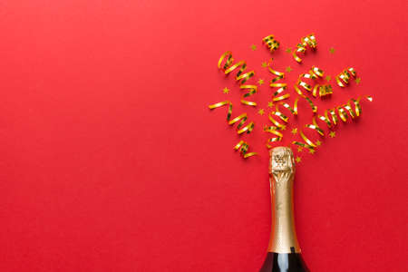 Creative flat lay composition with bottle of champagne and space for text on color background. Champagne bottle with colorful party streamers. holiday or christmas concept.の写真素材