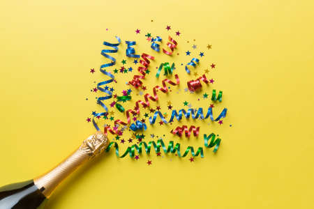 Creative flat lay composition with bottle of champagne and space for text on color background. Champagne bottle with colorful party streamers. holiday or christmas concept.の写真素材