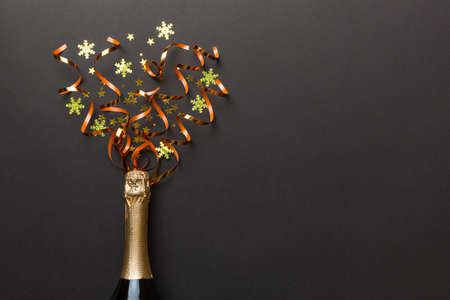 Creative flat lay composition with bottle of champagne and space for text on color background. Champagne bottle with colorful party streamers. holiday or christmas concept.の写真素材