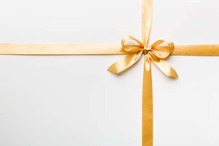 Top view of gold ribbon rolled and yellowbow isolated on colored background. Flat lay with copy space.の写真素材
