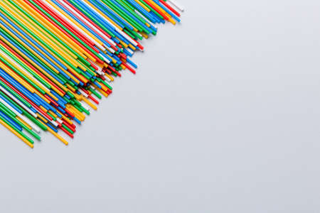 Heap of colorful plastic drinking straws on Colored background, flat lay. Copy Space for text.
