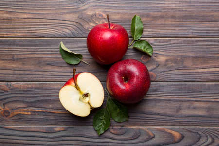 Fresh red apples with green leaves on wooden table. On wooden background. Top view free space for...