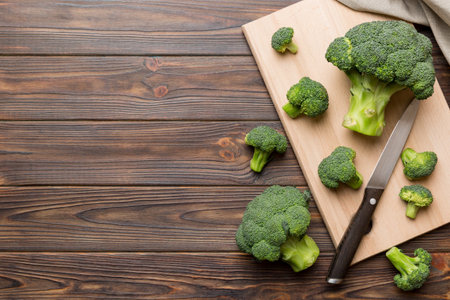fresh green broccoli on wooden cutting board with knife. Broccoli cabbage leaves. light background. Flat lay.の写真素材