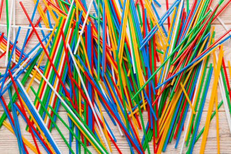 many multi-colored plastic tubes for cocktail on Colored background, top view.
