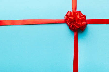 Top view of Red ribbon rolled and red bow isolated on colored background. Flat lay with copy space.