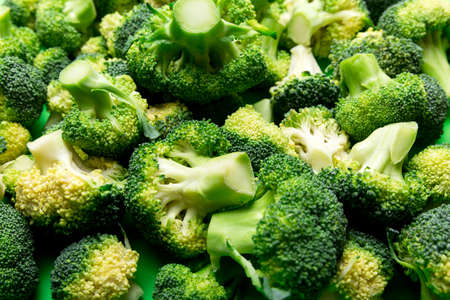 green fresh broccoli background close up on colored table. Vegetables for diet and healthy eating....