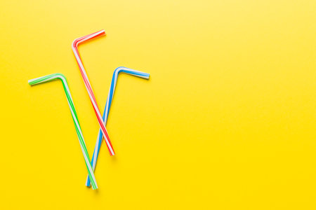 Drinking straws for party on Colored background. Top view of colorful plastic disposable straws for summer cocktails. different straws for juice with copy space.の写真素材