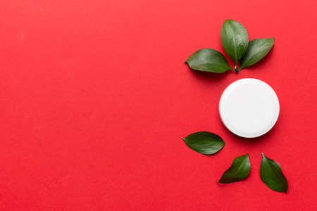 Organic cosmetic product with green leaves on color background. Copy space, flat lay.の写真素材