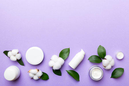 Organic cosmetic products with cotton flower and green leaves on wooden background. Copy space, flat lay.の写真素材