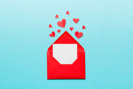 Red paper envelope with empty white card and heart on colored background. top view valentines day concept.の写真素材