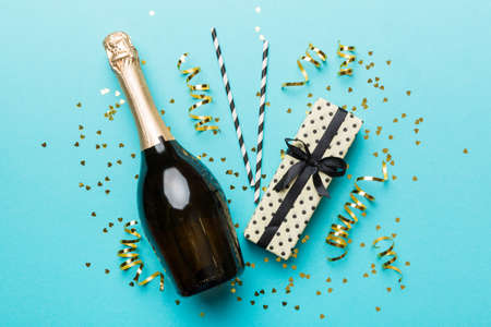 bottle of champagne with glasses and colorful confetti on colored background. top view flay lay.の写真素材