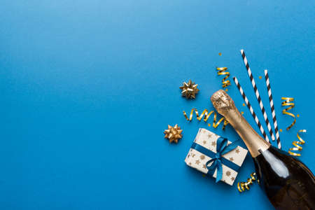 Bottle of champagne with colored glitter, confetti and gift box space for text on colorfull background, top view. Hilarious, christmas and birthday celebration.の写真素材