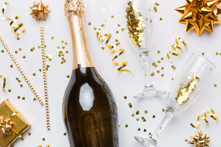 Bottle of champagne with colored glitter, confetti and gift box space for text on colorfull background, top view. Hilarious, christmas and birthday celebration.の写真素材