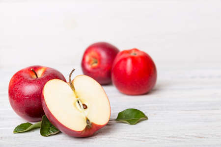 Fresh red apples with green leaves on wooden table. On wooden background. Top view free space for...