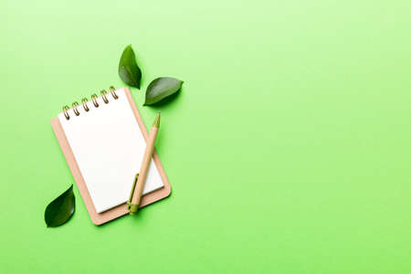 eco-friendly Empty notebook with pen and green leaf on Colored background for note.