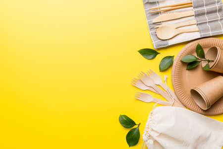set of empty reusable disposable eco-friendly plates, cups, utensils on light white colored table...