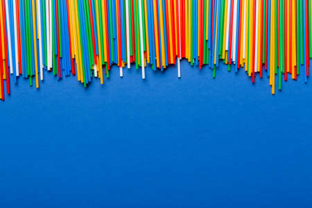 Heap of colorful plastic drinking straws on Colored background, flat lay. Copy Space for text.の写真素材