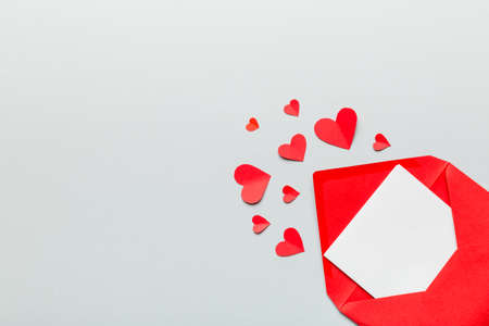 Red paper envelope with empty white card and heart on colored background. top view valentines day concept.の写真素材