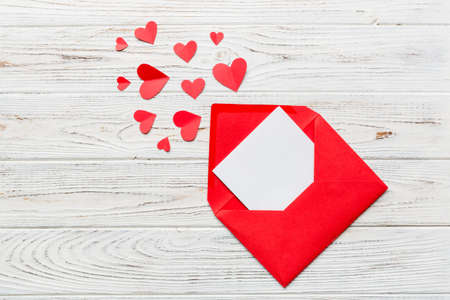 Red paper envelope with empty white card and heart on colored background. top view valentines day concept.の写真素材