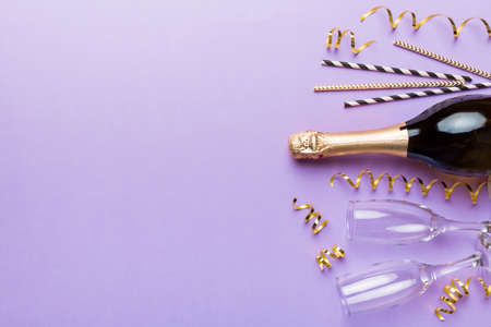 Champagne bottle, glitter and straws on color background. top view. Hilarious, christmas and birthday celebration.の写真素材