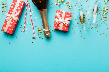 Bottle of champagne with colored glitter, confetti and gift box space for text on colorfull background, top view. Hilarious, christmas and birthday celebration.の写真素材