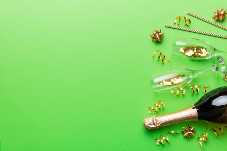 Champagne bottle, glitter and straws on color background. top view. Hilarious, christmas and birthday celebration.の写真素材